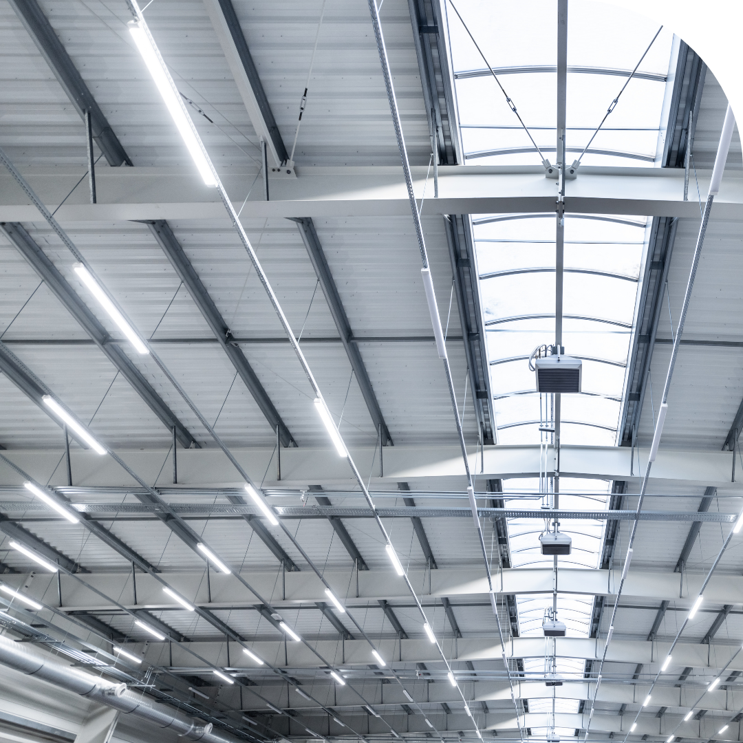 Electrician installing industrial high-bay LED lighting in a London warehouse