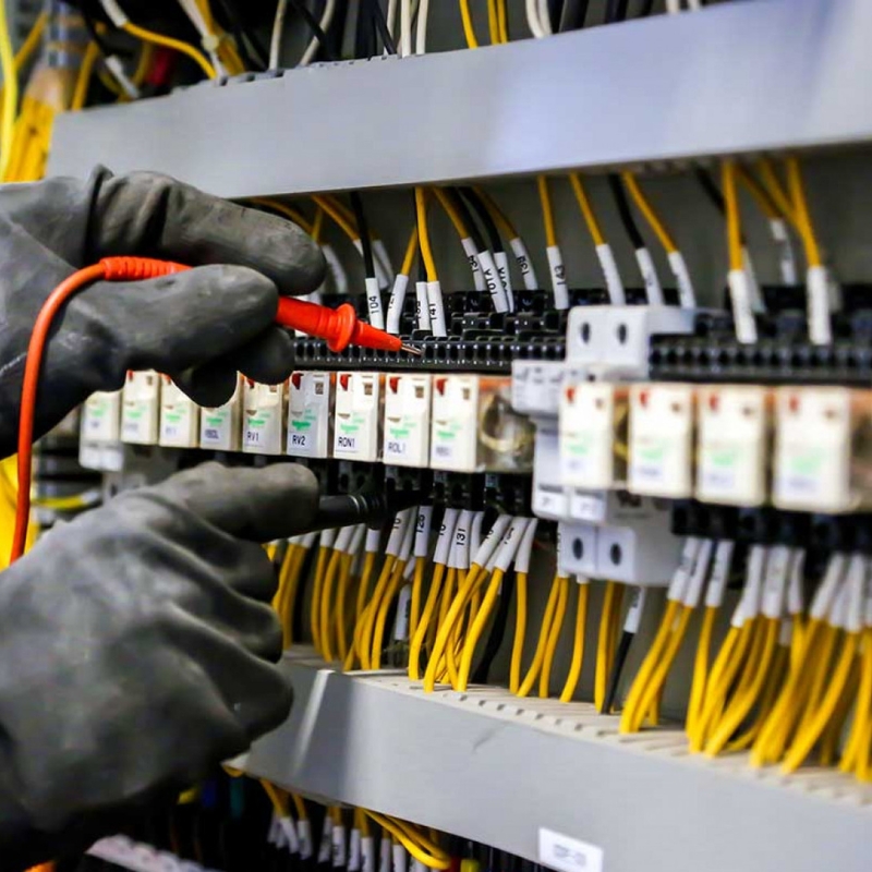 Industrial electrician performing emergency repair on a faulty 3-phase panel in a London factory